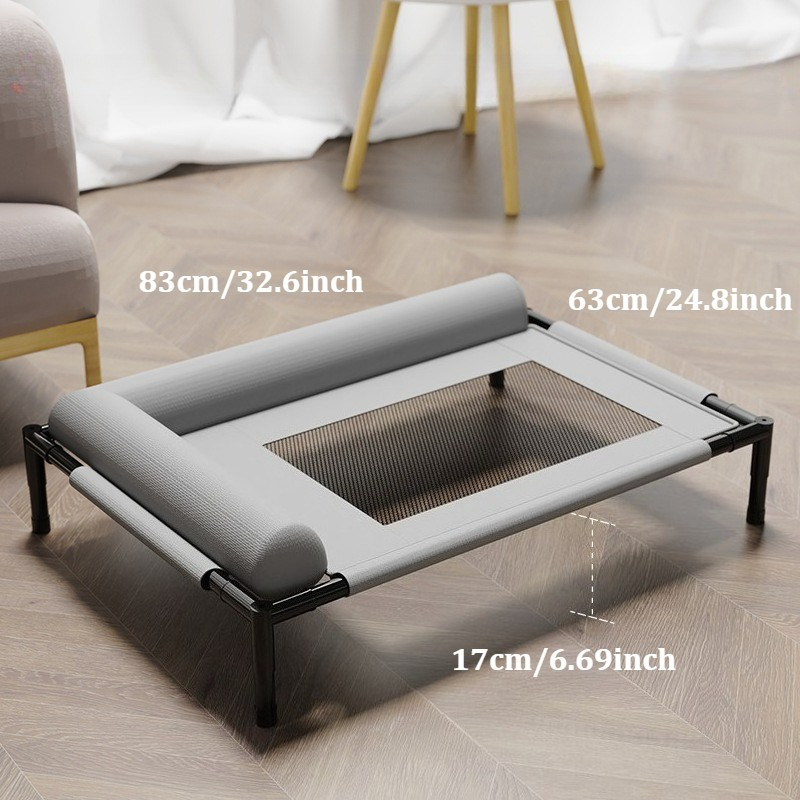 Grey raised dog bed on a wooden floor beside a chair, with its length, width and height marked