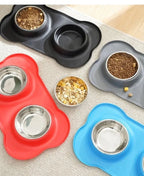 Grey, red and blue bone-shaped silicone mats with steel bowls holding food, seen from above