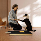 Dog nail scratch board in use by a black and white dog, with a woman kneeling beside it